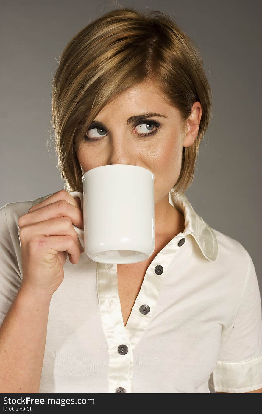 Portrait of beautiful blond girl holding a white cup on grey background. Portrait of beautiful blond girl holding a white cup on grey background