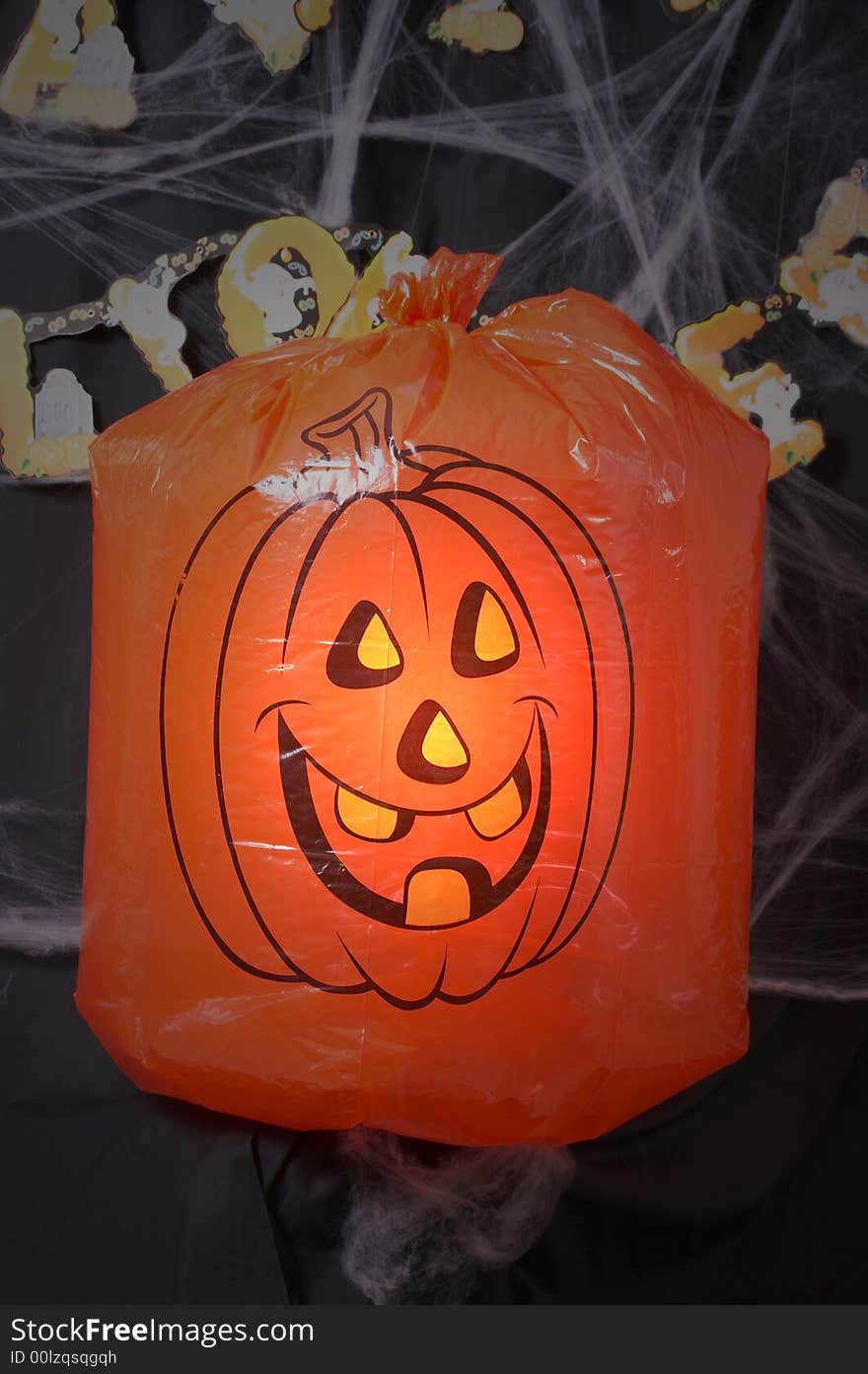 A pumpkin lawn bags under a spotlight