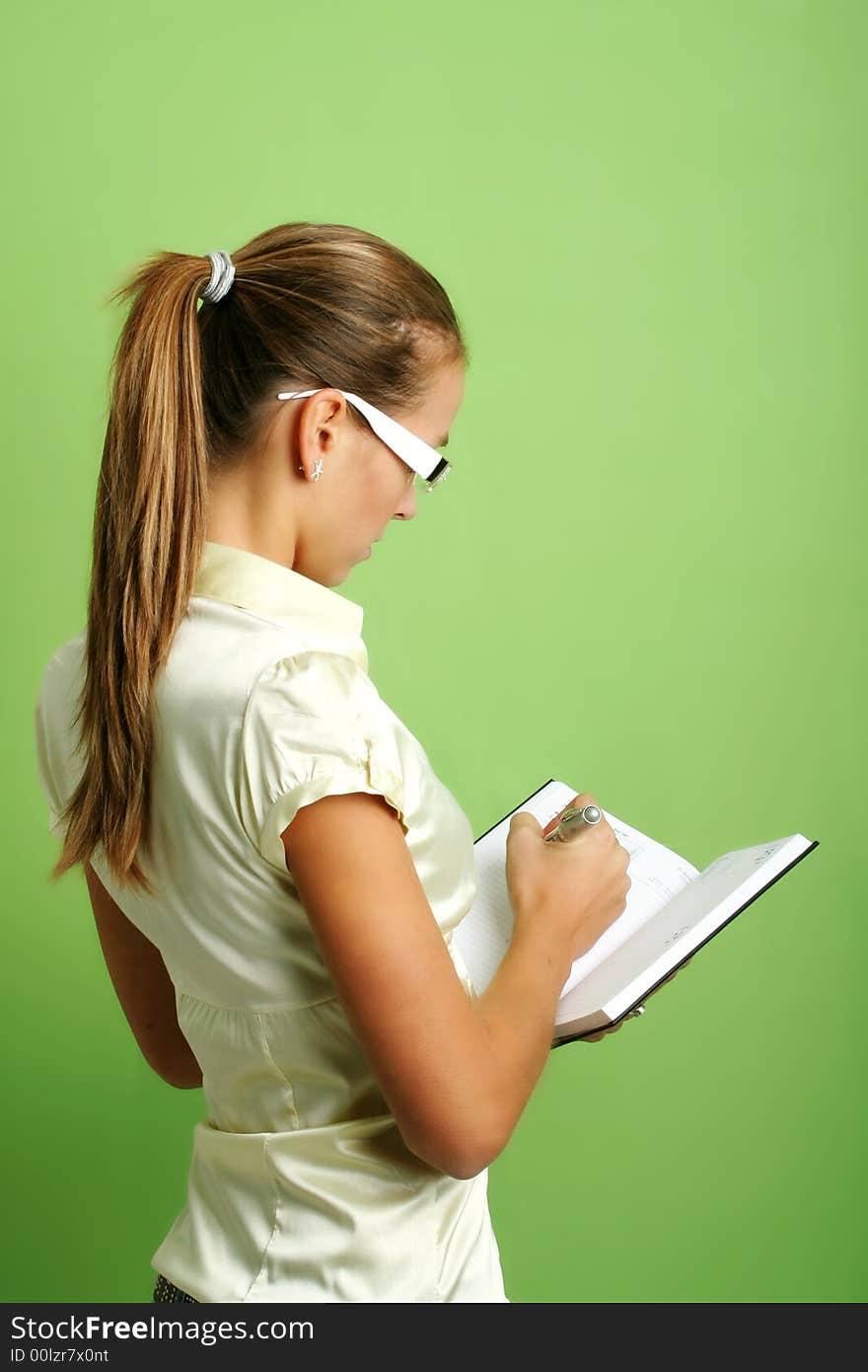 Business portrait of a young and successful woman writing at a folder. Business portrait of a young and successful woman writing at a folder