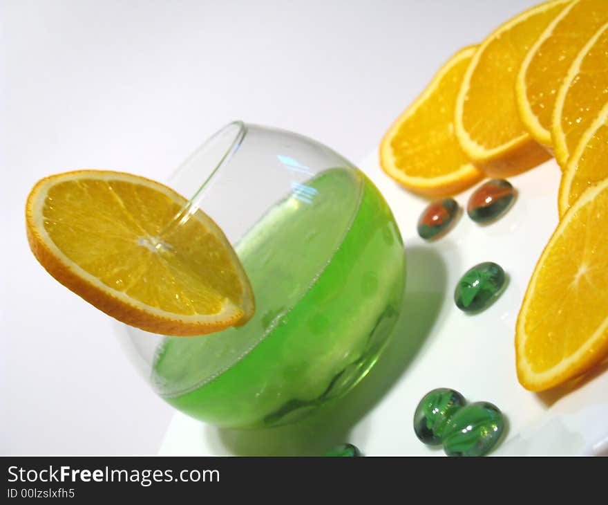 Sphere glass with bright green shower gel inside on white plate with fresh juicy oranges. Sphere glass with bright green shower gel inside on white plate with fresh juicy oranges