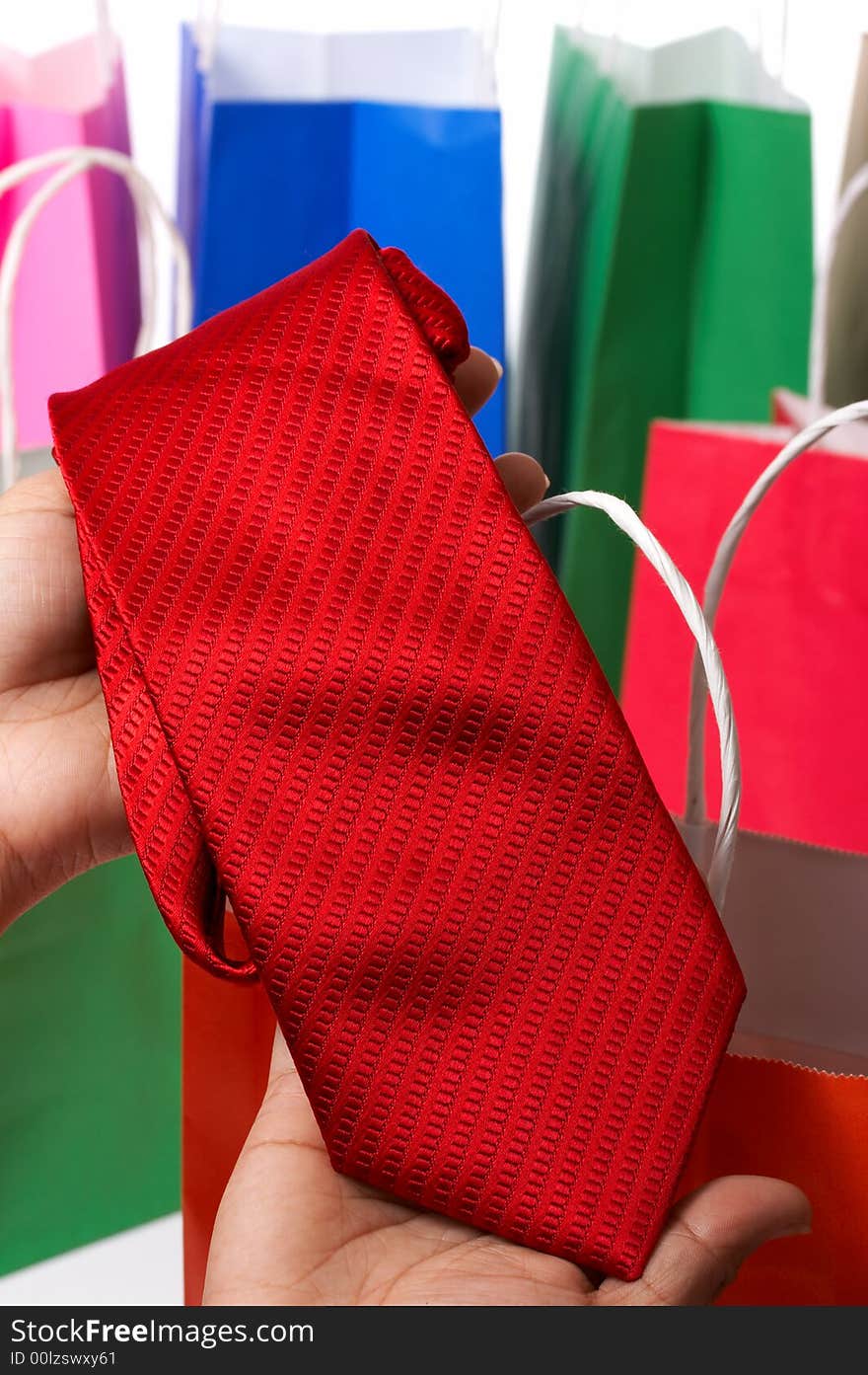 Holding a red necktie with some shopping bags on the background