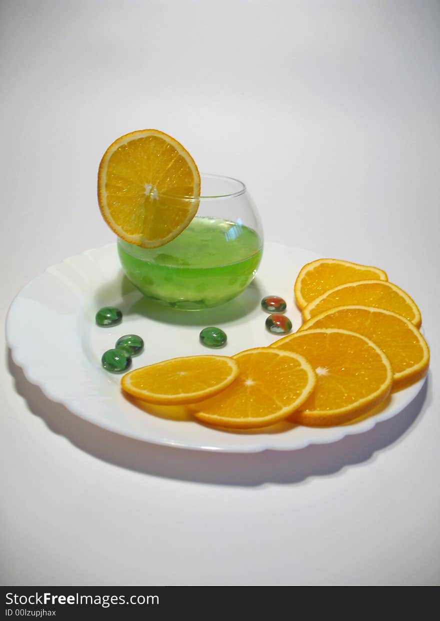 Sphere glass with bright green shower gel inside on white plate with fresh juicy oranges. Sphere glass with bright green shower gel inside on white plate with fresh juicy oranges