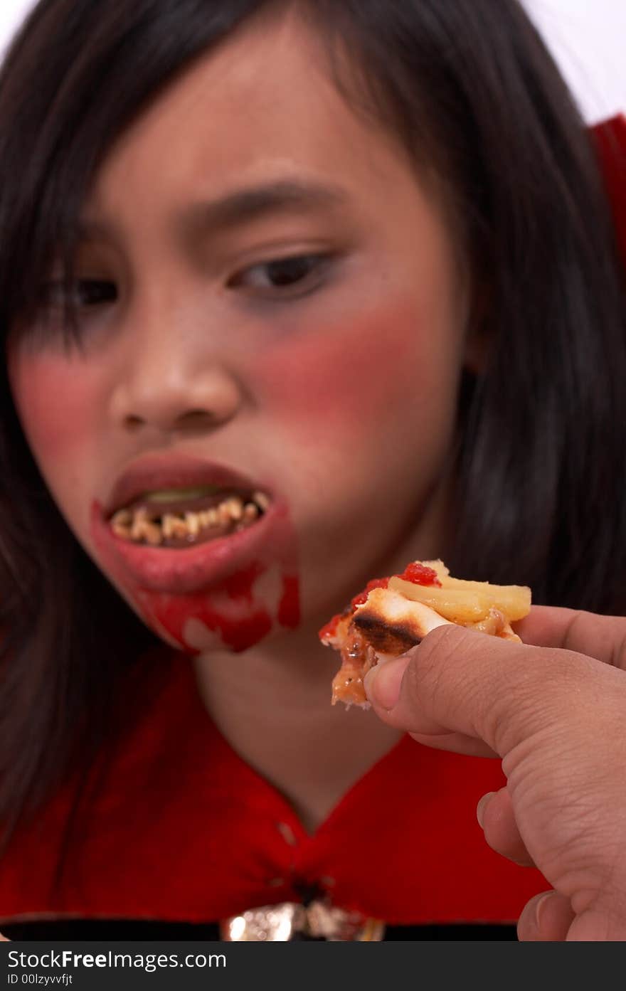 A vampire with a bloody mouth looking at a pizza. A vampire with a bloody mouth looking at a pizza