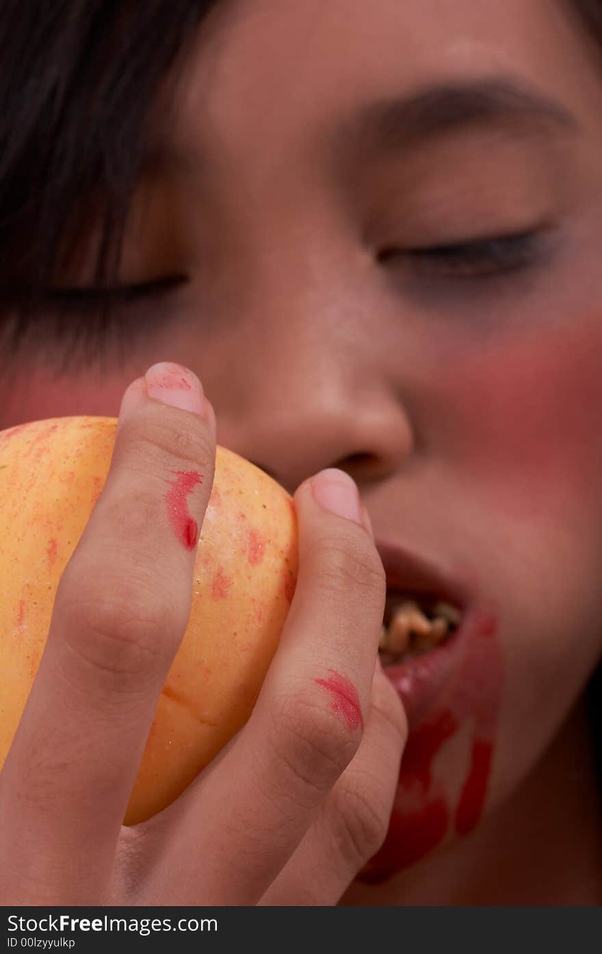 A vampire with a bloody mouth holding an apple. A vampire with a bloody mouth holding an apple