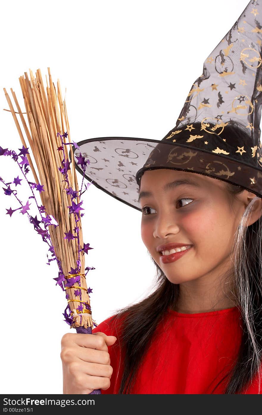 A young girl dressed in a witch costume looking at her broomstick