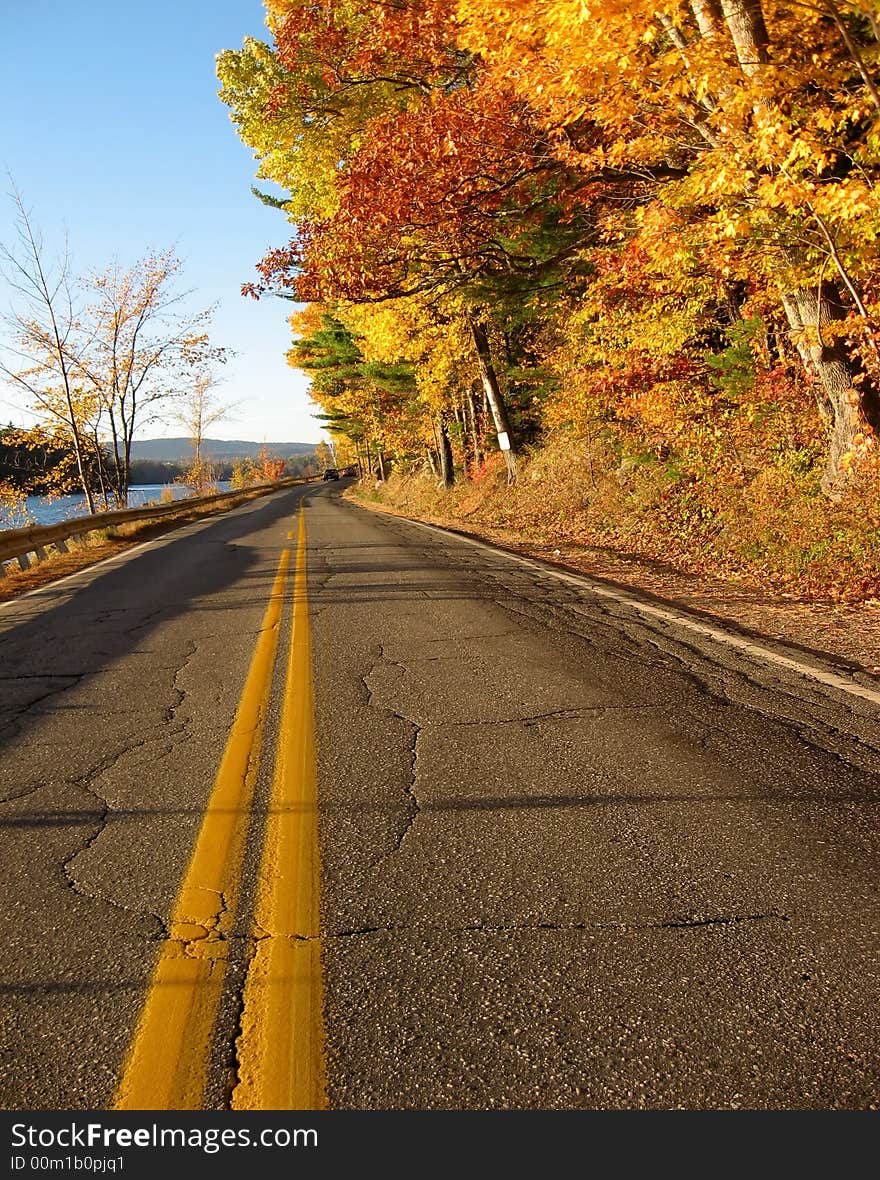 Along a rural two lane road in Maine, an Autumn view with red and yellow maple trees. Along a rural two lane road in Maine, an Autumn view with red and yellow maple trees