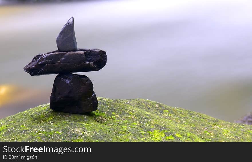 Stones arrangement on rock surface captured against natural stream of waterfall. Stones arrangement on rock surface captured against natural stream of waterfall.