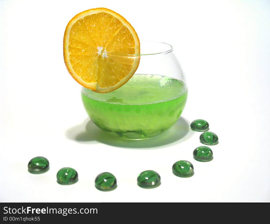 Sphere glass filled with bright green shower gel and green glass pebbles with juicy orange. Sphere glass filled with bright green shower gel and green glass pebbles with juicy orange