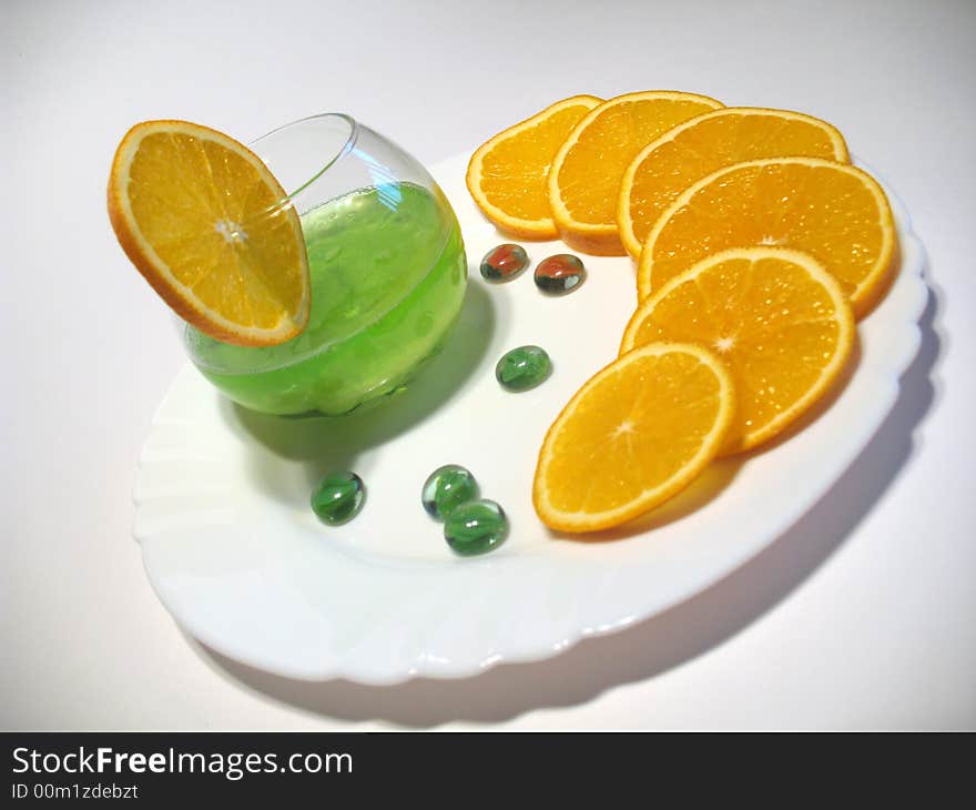 Sphere glass with bright green shower gel inside on white plate with fresh juicy oranges. Sphere glass with bright green shower gel inside on white plate with fresh juicy oranges