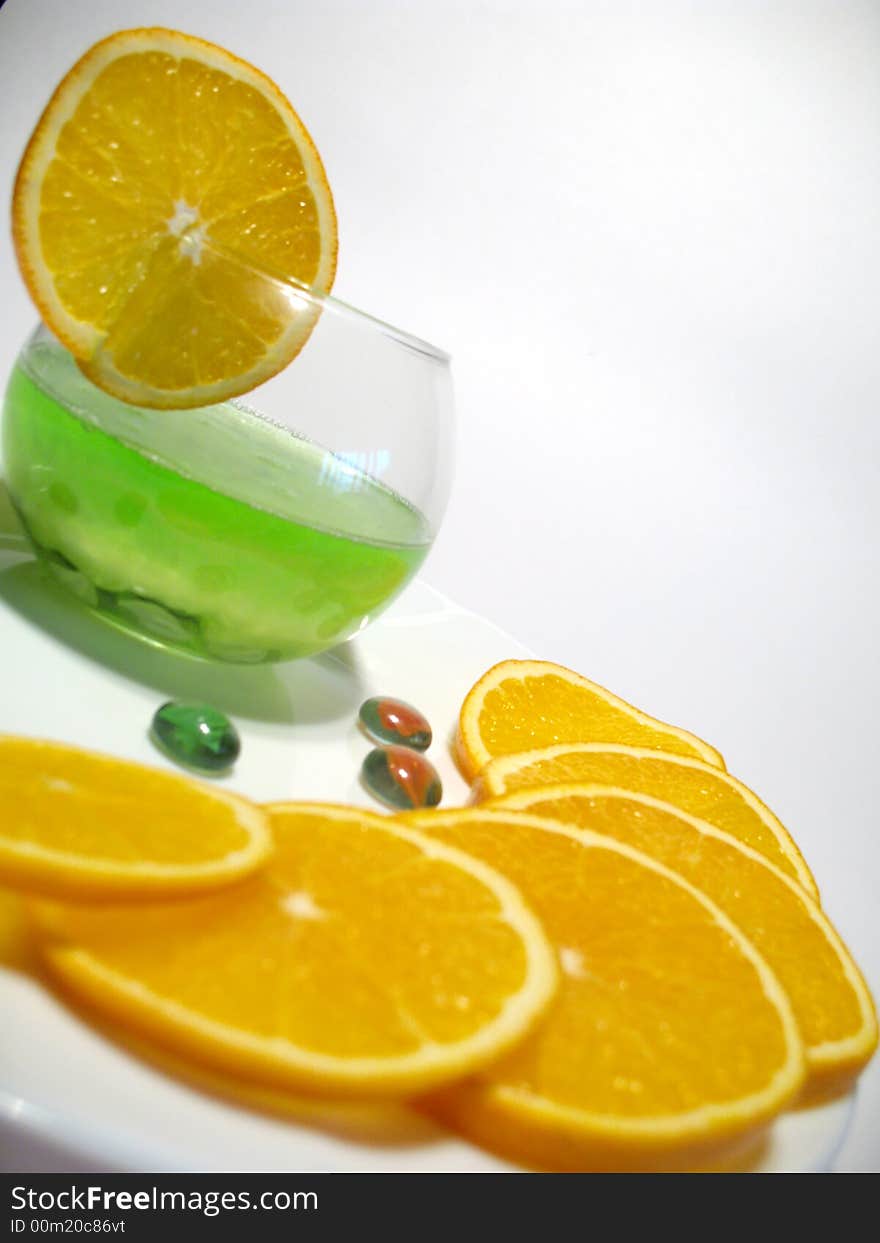 Sphere glass with bright green shower gel inside on white plate with fresh juicy oranges. Sphere glass with bright green shower gel inside on white plate with fresh juicy oranges