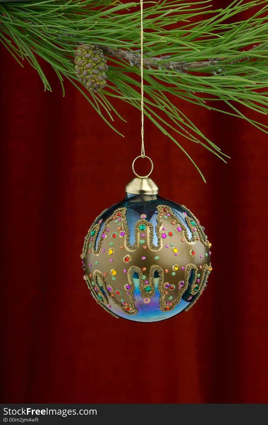 Christmas tree ornament with a pine tree branch in the top of the image, a blue hand painted decoration being the main focus. Christmas tree ornament with a pine tree branch in the top of the image, a blue hand painted decoration being the main focus