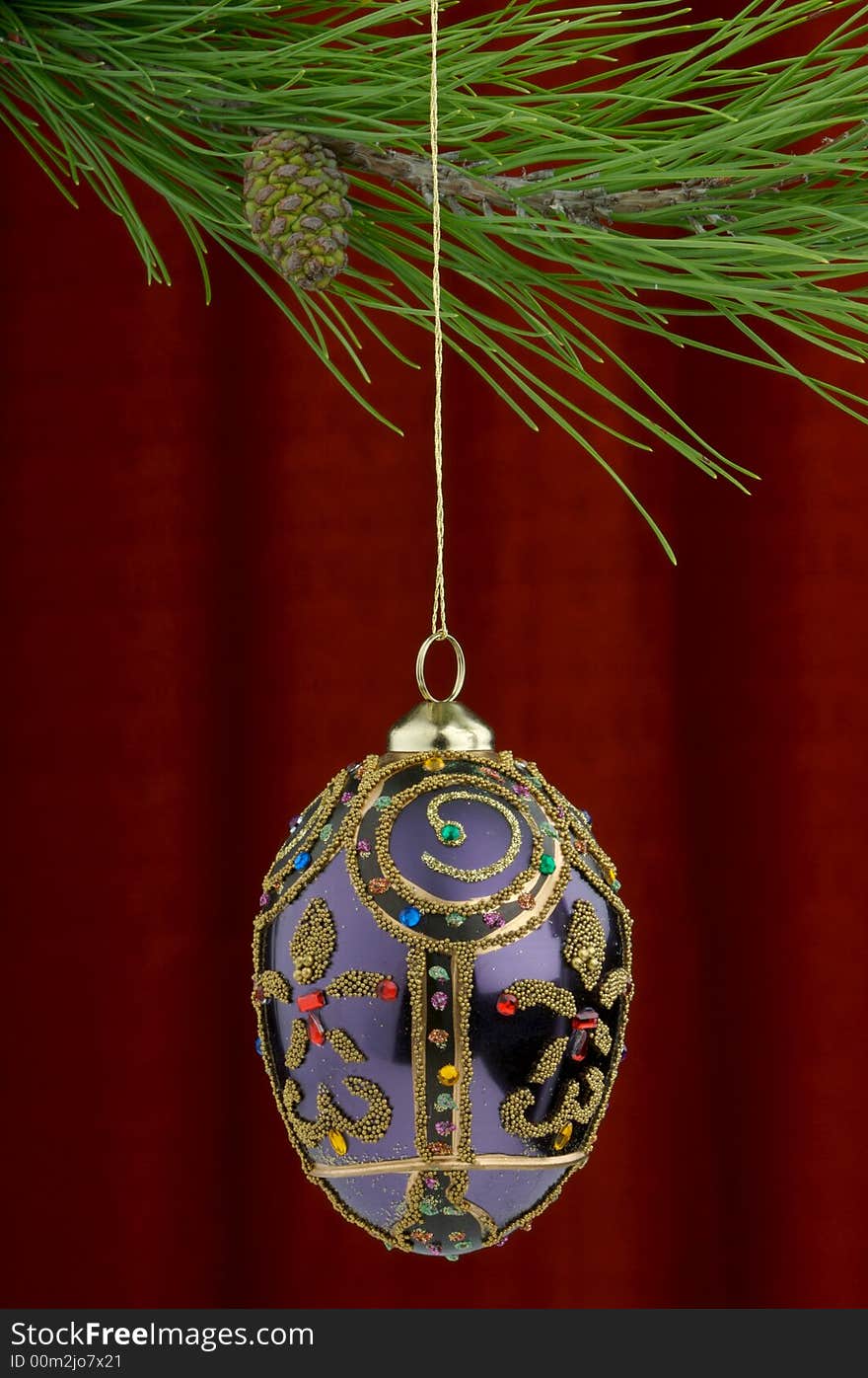 Christmas tree ornament with a pine tree branch in the top of the image, a purple hand painted decoration being the main focus. Christmas tree ornament with a pine tree branch in the top of the image, a purple hand painted decoration being the main focus