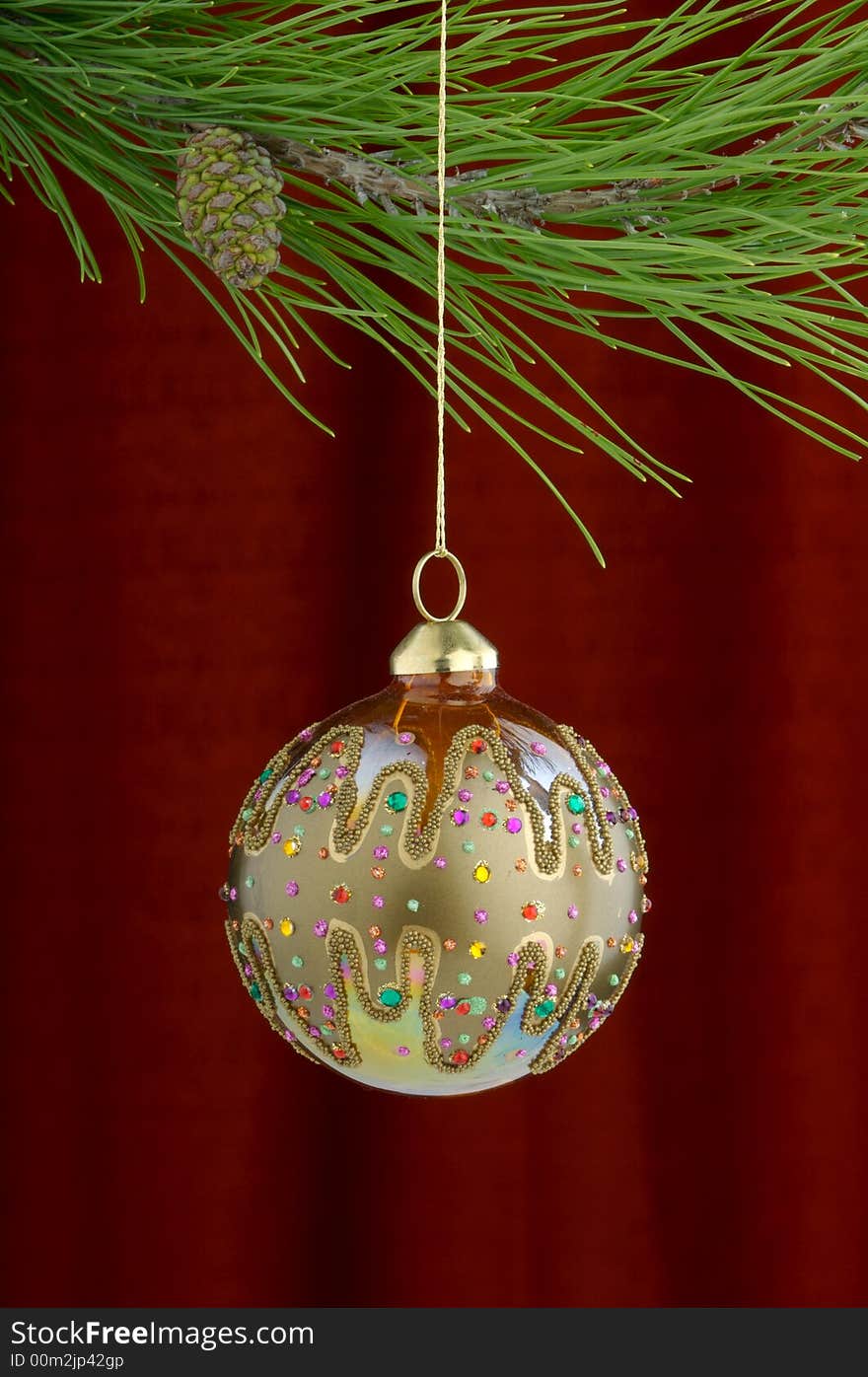 An image of gold Christmas ornaments on a burgundy background. An image of gold Christmas ornaments on a burgundy background