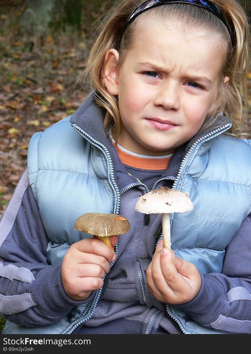 Small boy with mushrooms in the forest