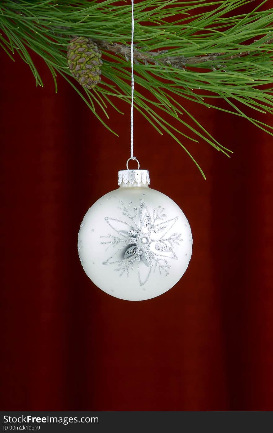 An image of a white and silver Christmas ornament on a burgundy background. An image of a white and silver Christmas ornament on a burgundy background