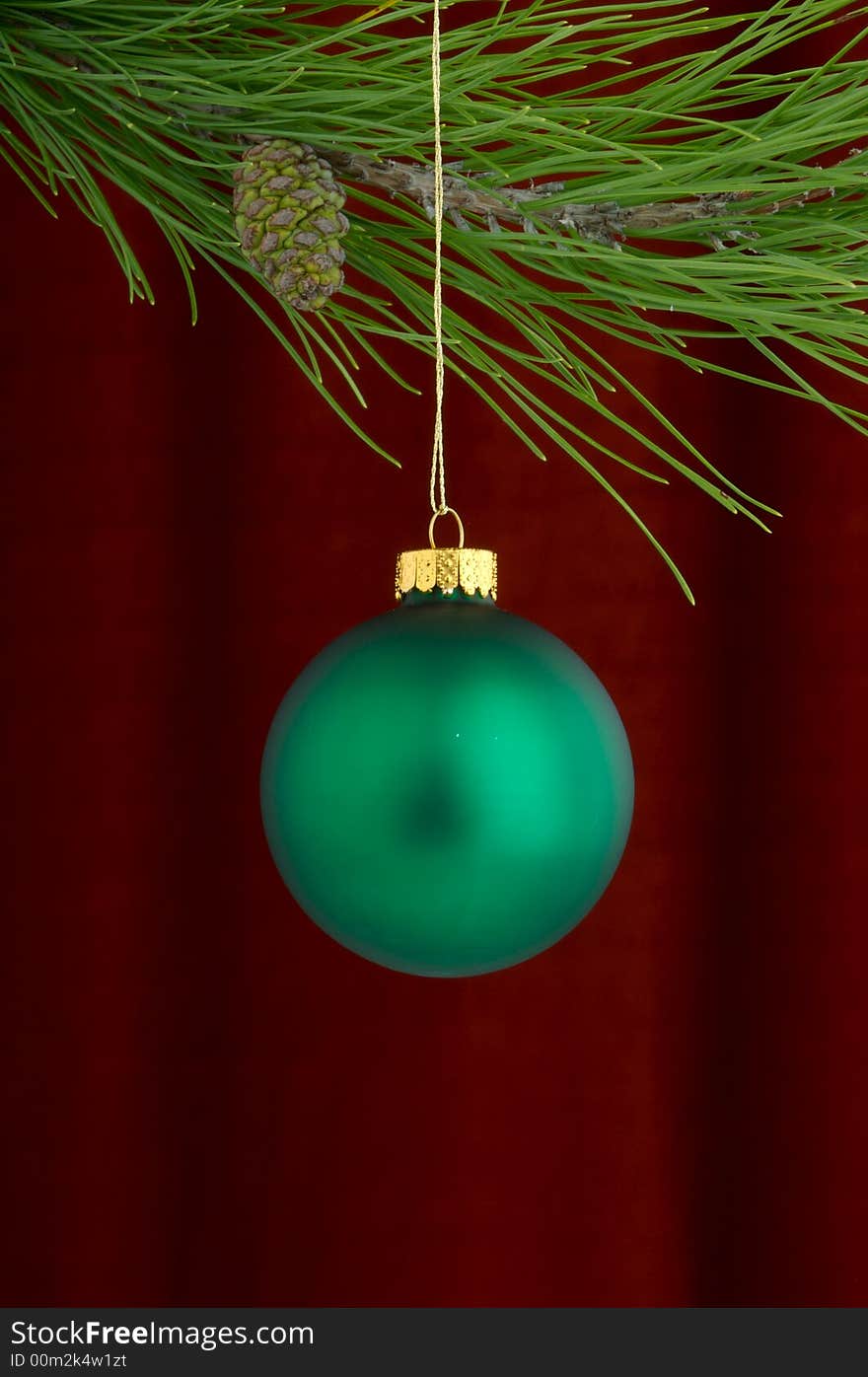 An image of a green Christmas ornament on a burgundy background. An image of a green Christmas ornament on a burgundy background