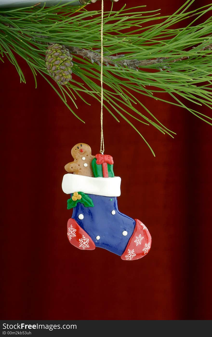 An image of a stocking Christmas ornament on a burgundy background. An image of a stocking Christmas ornament on a burgundy background