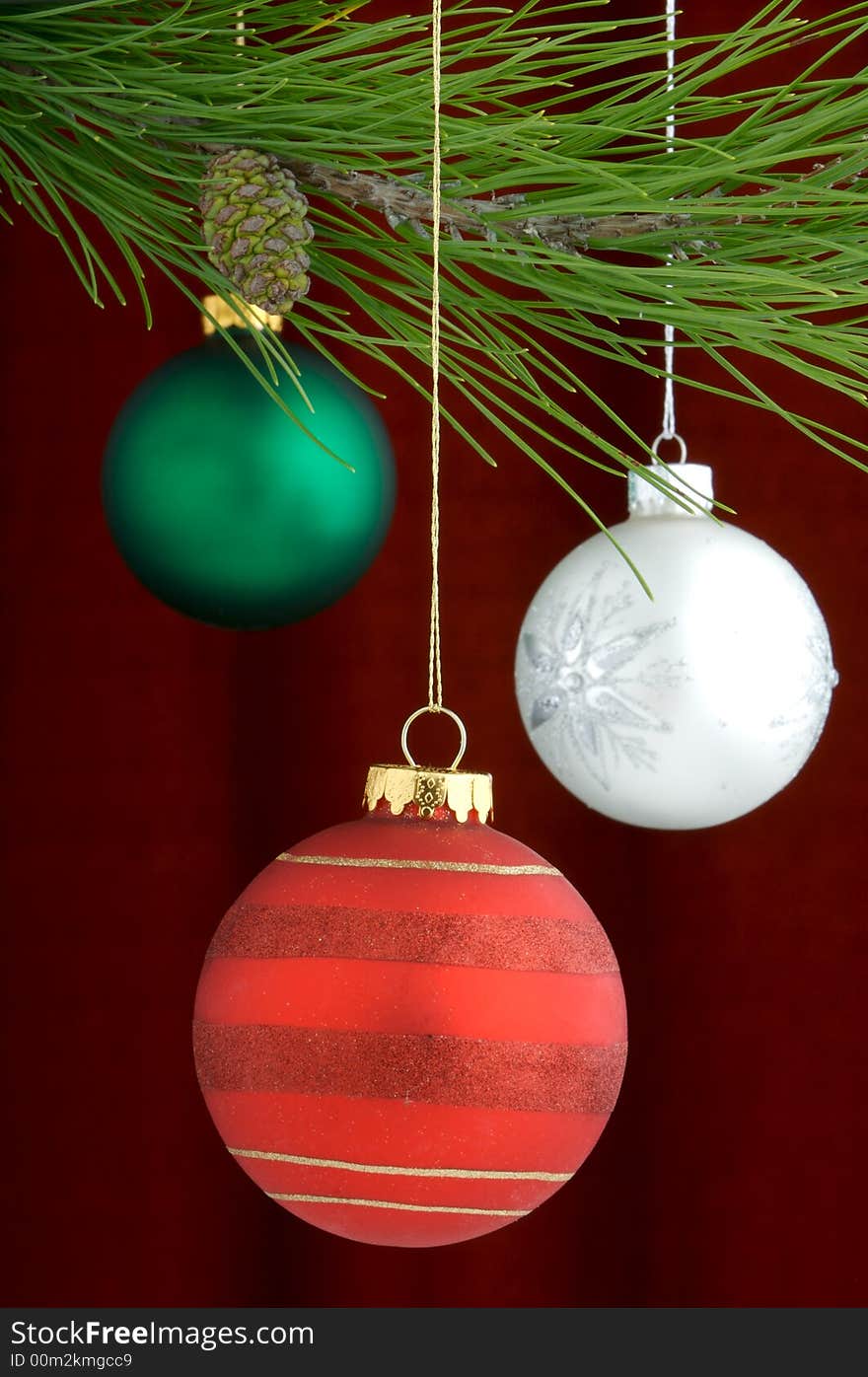 An image of multicolored Christmas ornaments on a burgundy background. An image of multicolored Christmas ornaments on a burgundy background