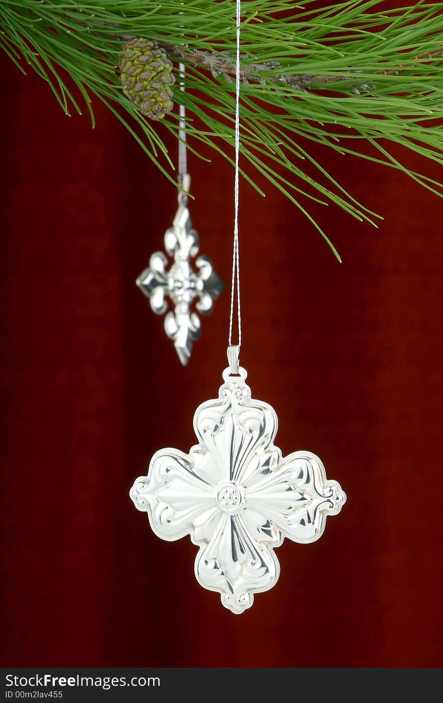 An image of silver Christmas ornaments on a burgundy background. An image of silver Christmas ornaments on a burgundy background