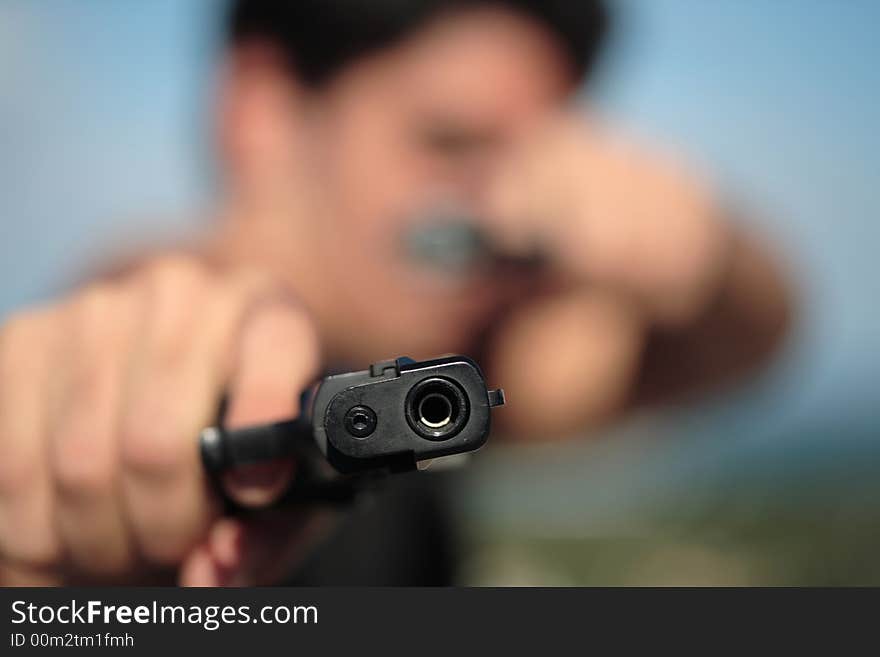 A young, robust man, in his 20's with dark hair pointing 2 pistols to the camera. A young, robust man, in his 20's with dark hair pointing 2 pistols to the camera.