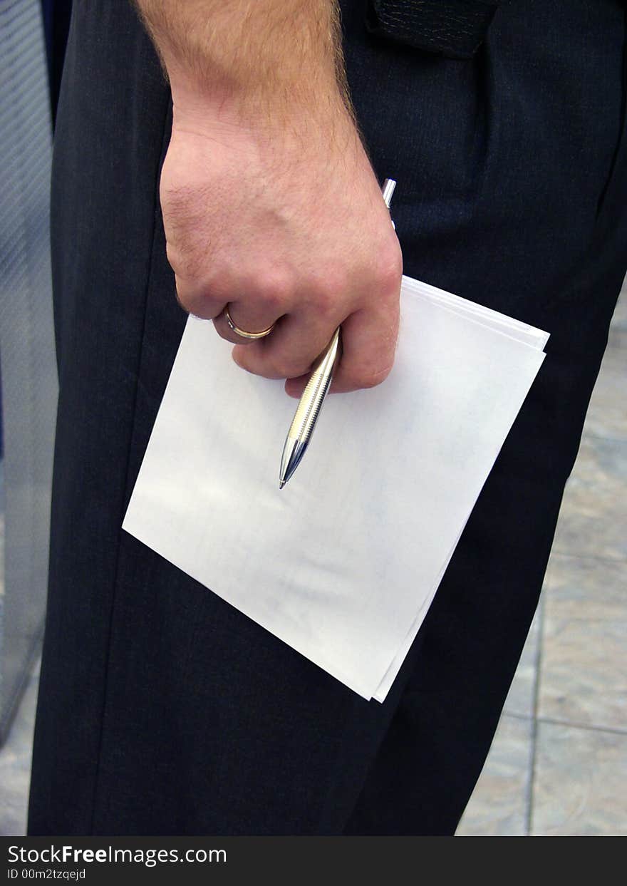 Hand holding pen and a paper. Reflection before a writing.