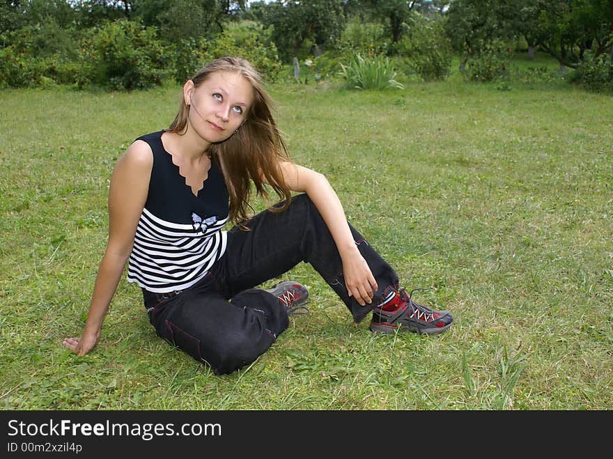 The girl sits on a grass. The girl sits on a grass