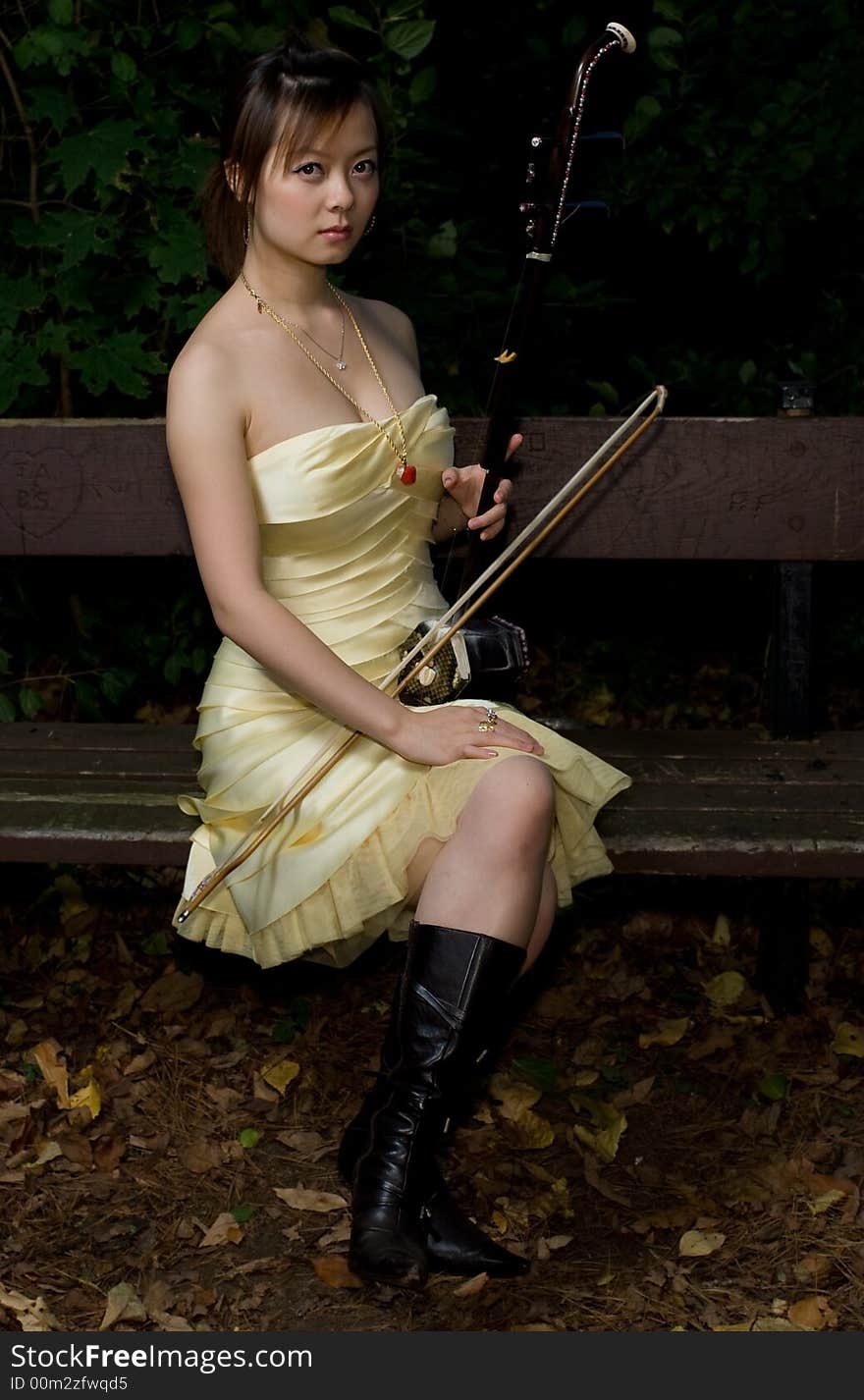 A girl holding a Erhu sitting on a long chair. A girl holding a Erhu sitting on a long chair