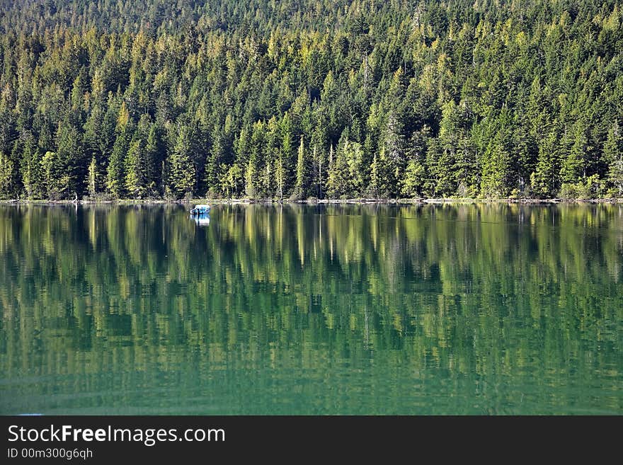 A white boat on the lake surrounded by a dense wood. A white boat on the lake surrounded by a dense wood