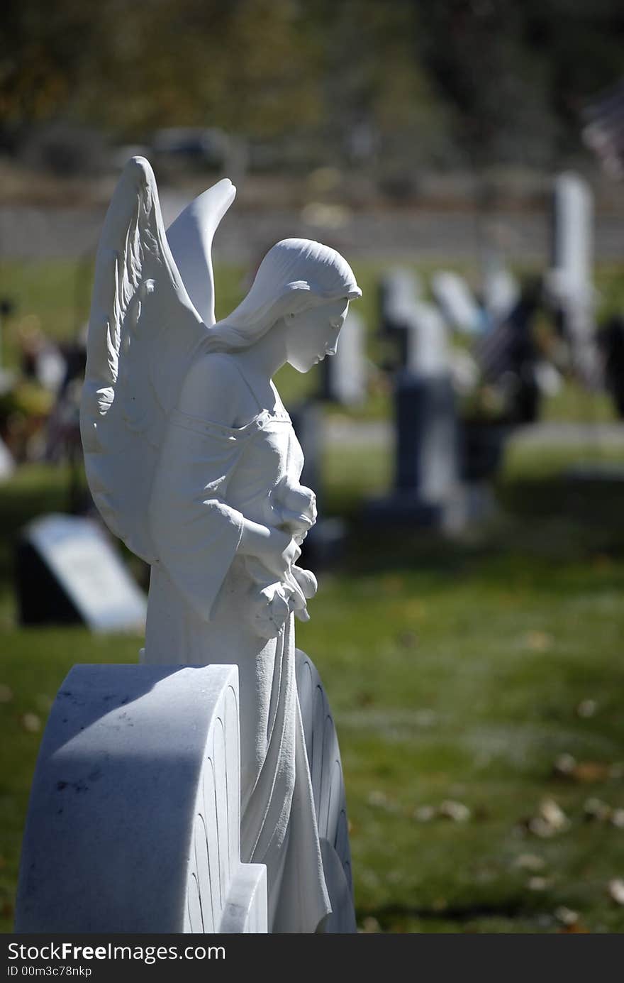 White marble statue of a winged angel in grave yard cemetery. White marble statue of a winged angel in grave yard cemetery