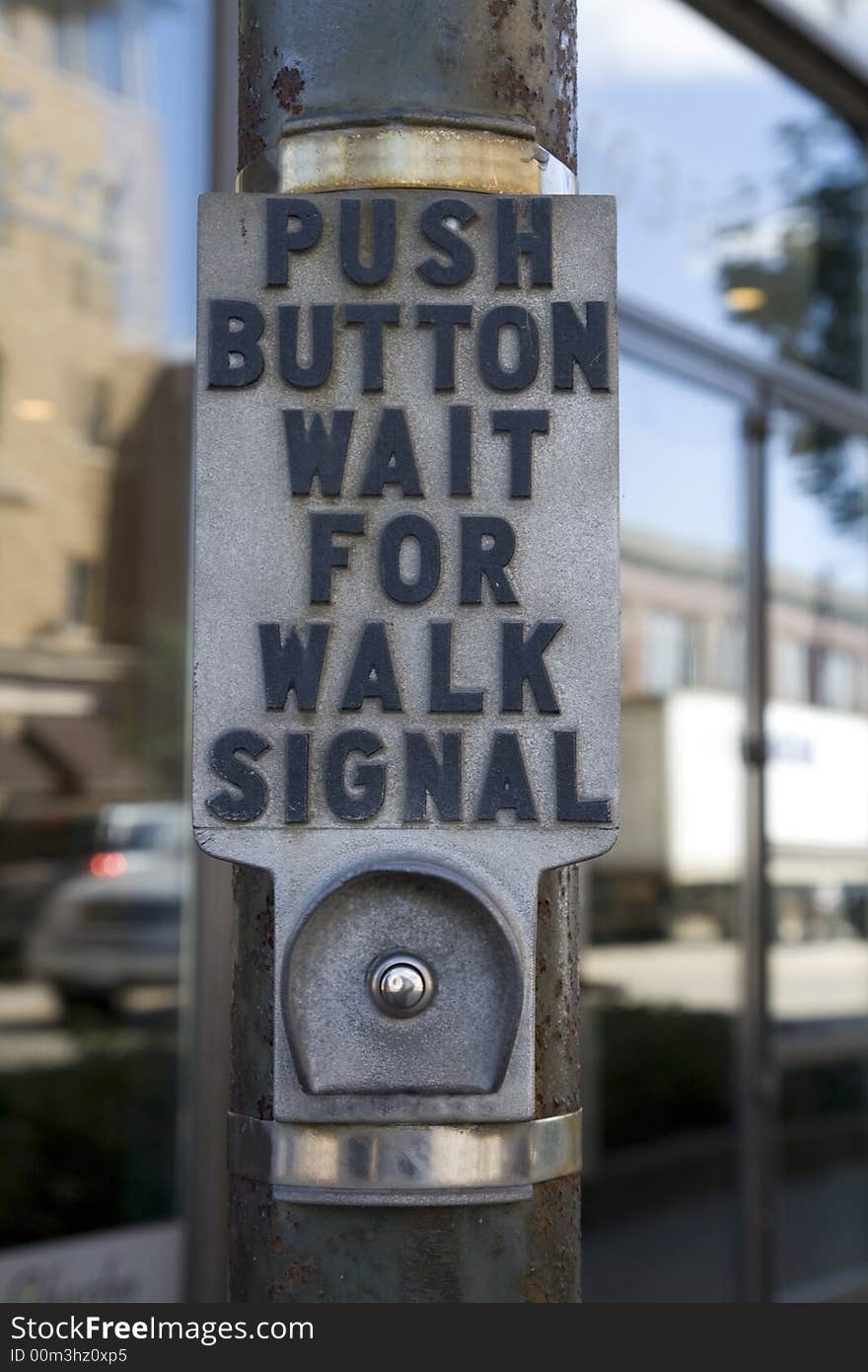 Crosswalk button on pole at intersection with sign