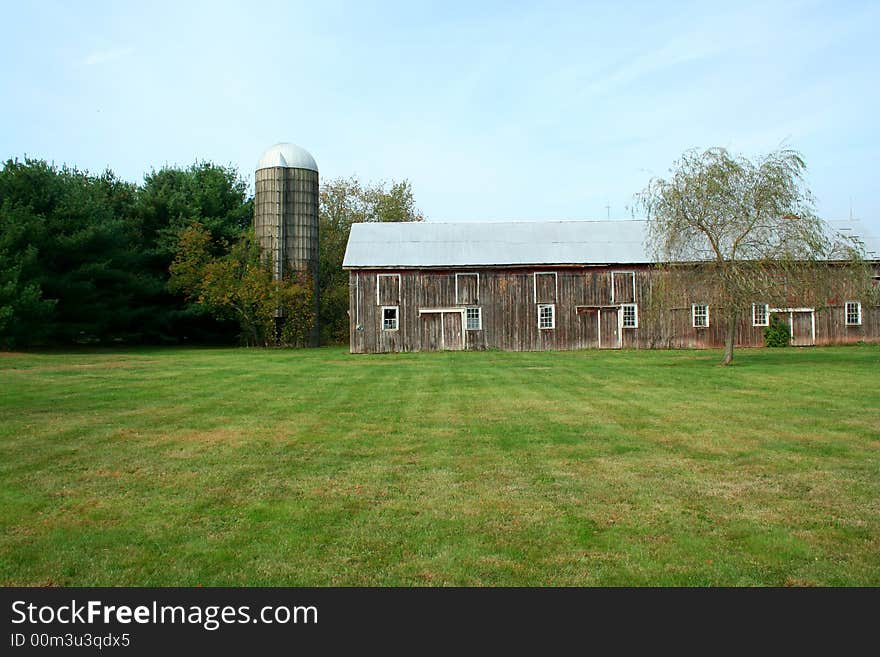 A Barn and silo with trees and grass