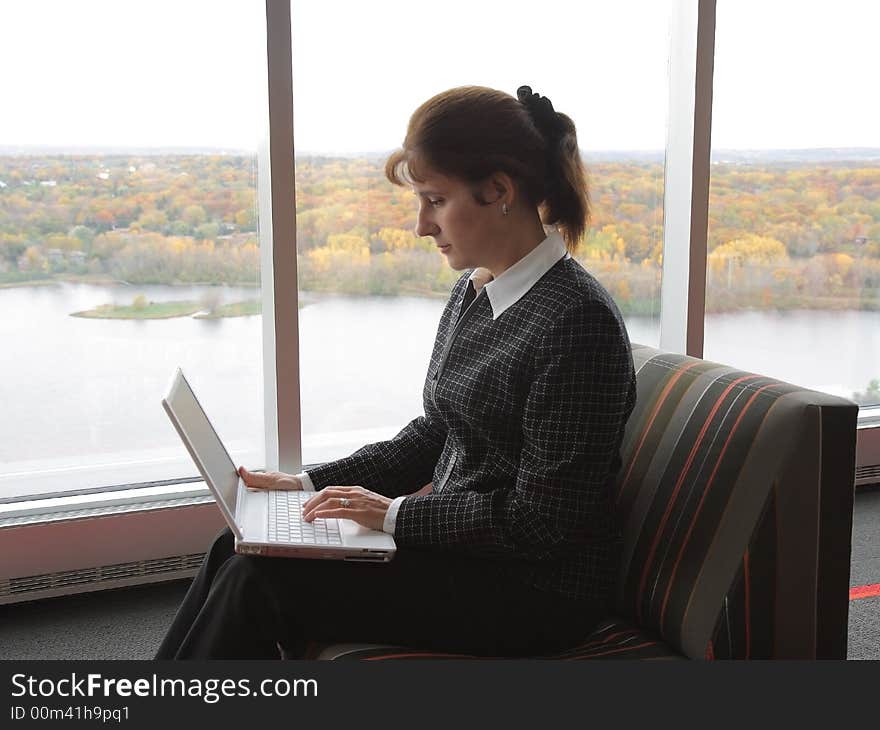 Business woman working on laptop in the hall of office building. Business woman working on laptop in the hall of office building