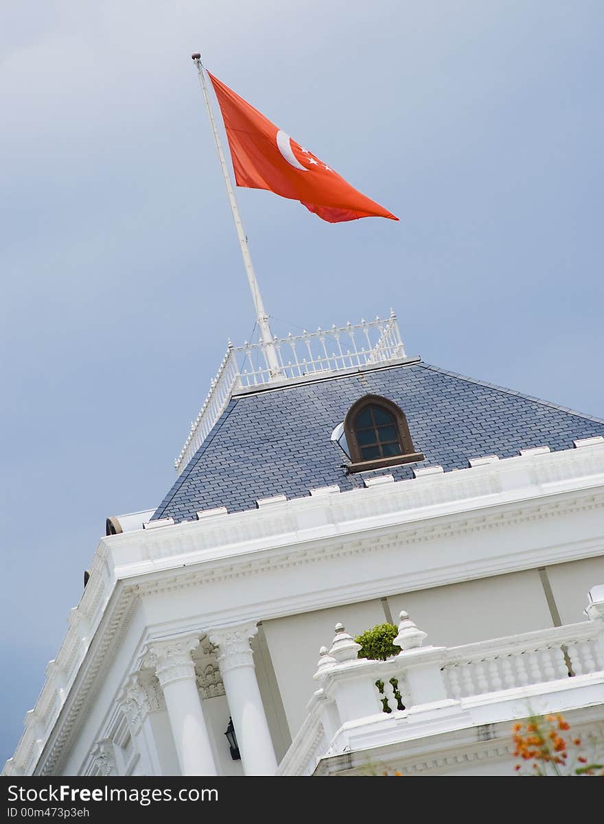 A grand building all decked in white with a red flag. Taken in Singapore Istana.