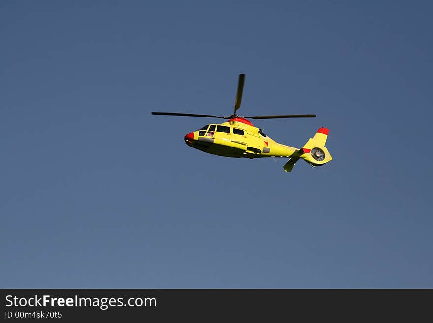 Side view of a yellow rescue helicopter in high flight. Side view of a yellow rescue helicopter in high flight.