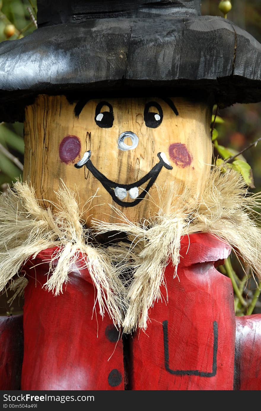 A hand carved wooden scarecrow used in a beautiful seasonal display.