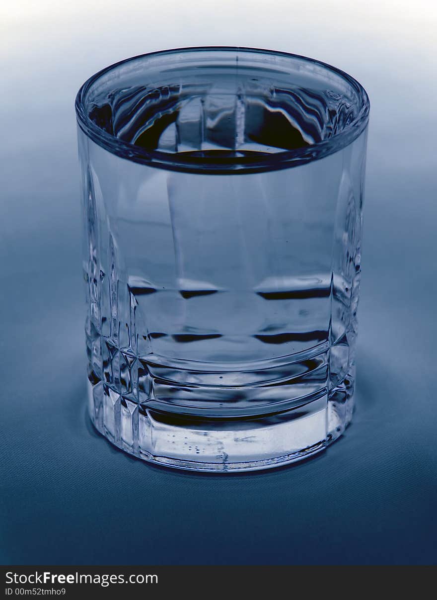 A glass filled with water on a blue/white background. A glass filled with water on a blue/white background