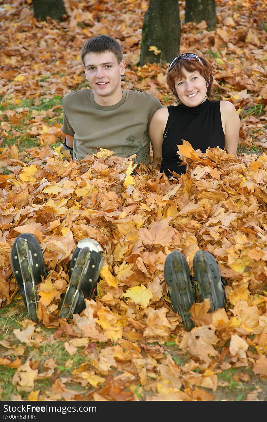 Young roller couple sit in yellow leaves