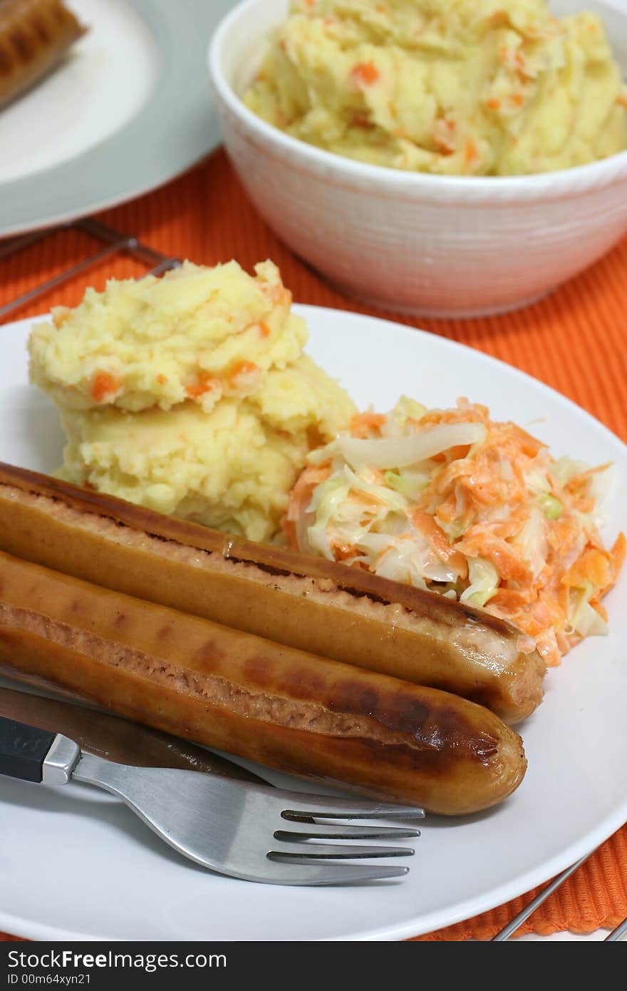 Large frankfurters with carrot and cabbage coleslaw and mash for dinner. Large frankfurters with carrot and cabbage coleslaw and mash for dinner