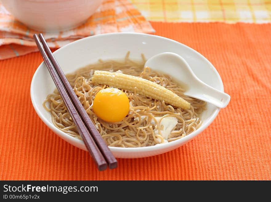 Brown Chinese buckwheat noodles with egg and baby corn in light soup