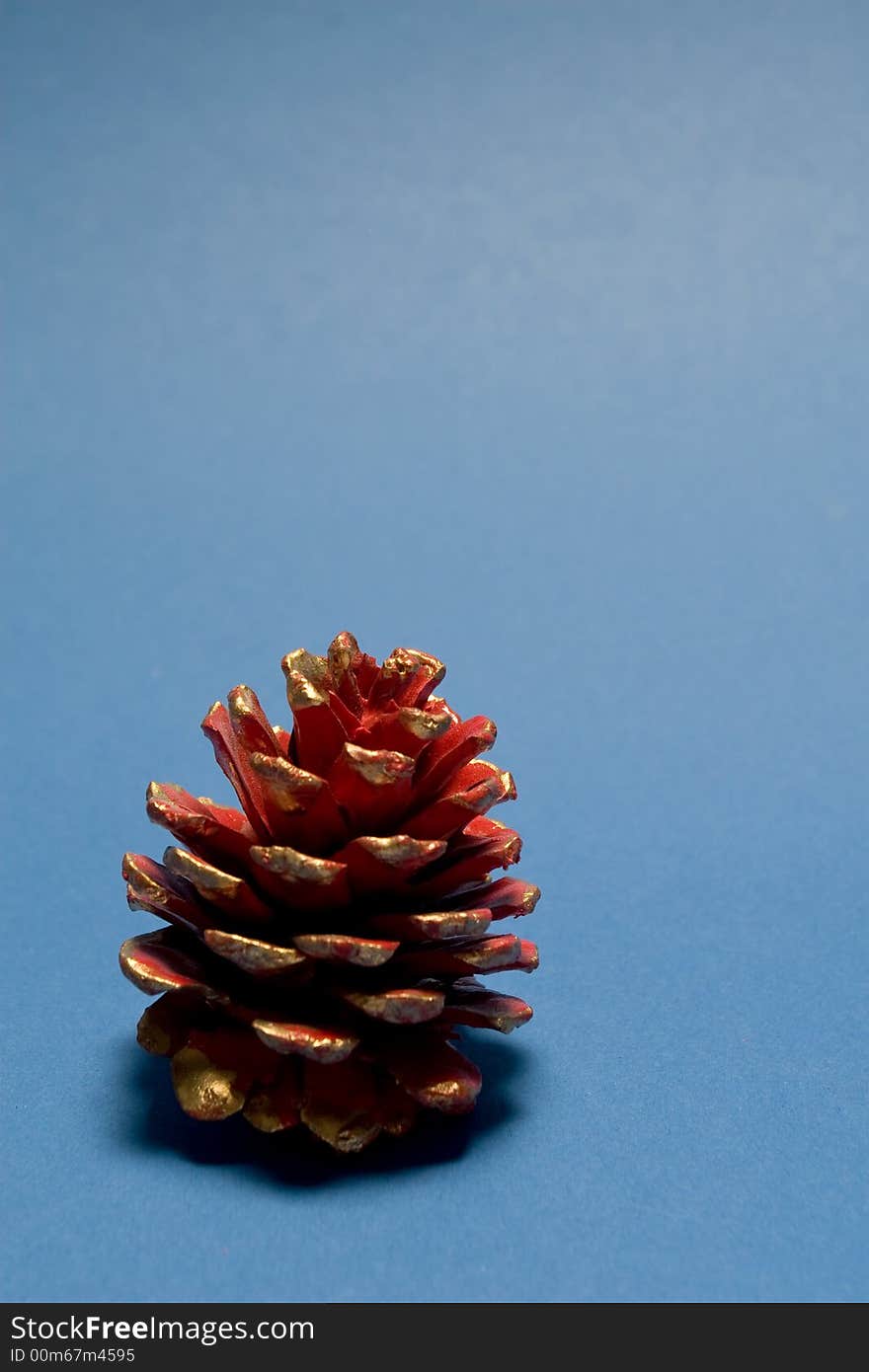 Red christmas pine cone isolated on blue background. Red christmas pine cone isolated on blue background