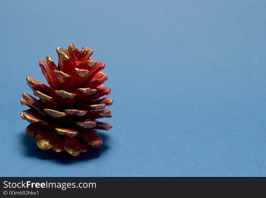 Red christmas pine cone on blue background. Red christmas pine cone on blue background