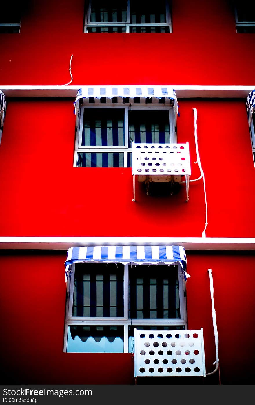 The front facade of a brightly colored building featuring striped window awnings. The front facade of a brightly colored building featuring striped window awnings.