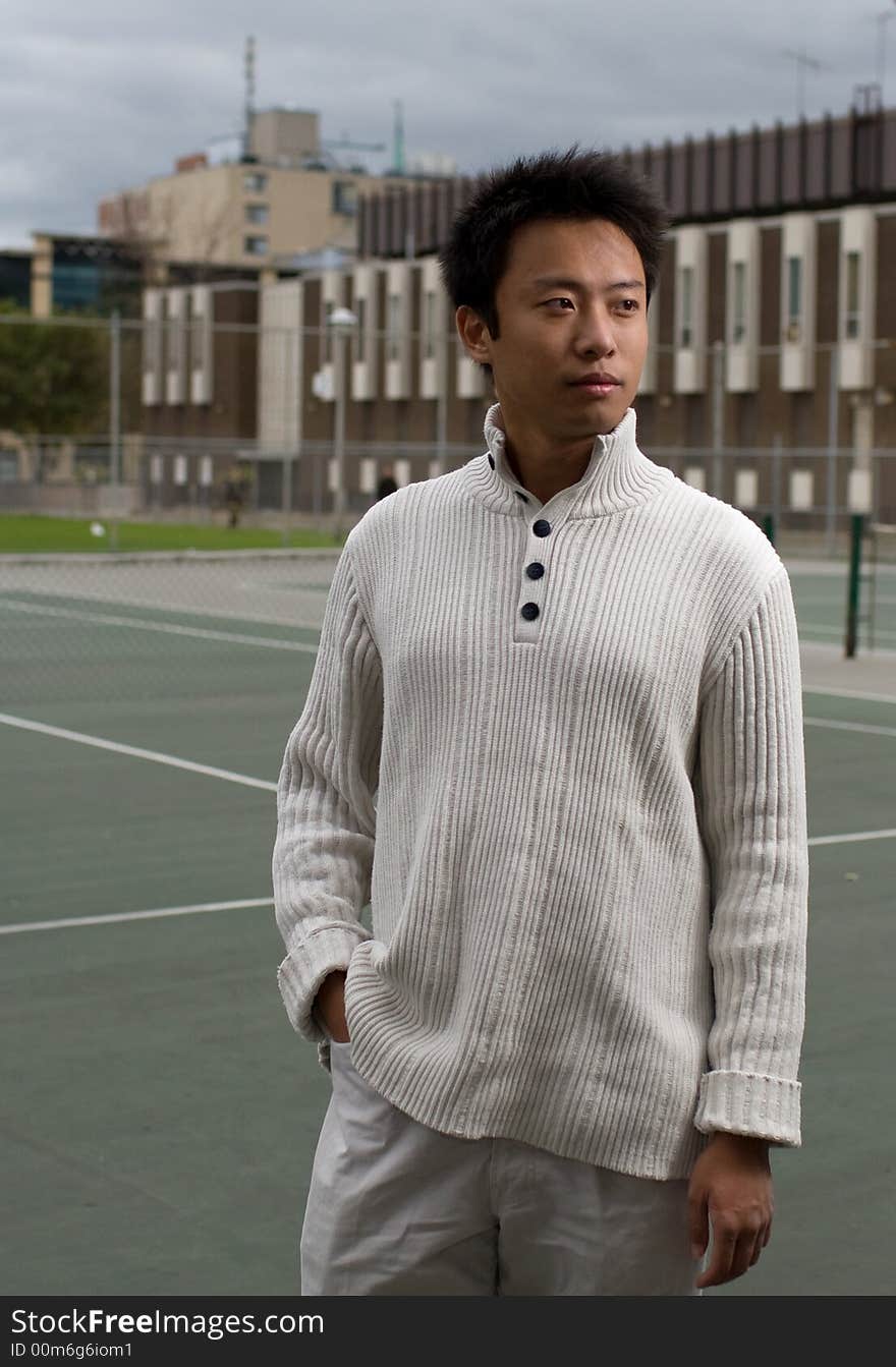 A boy standing in tennis court wearing sports clothing. A boy standing in tennis court wearing sports clothing