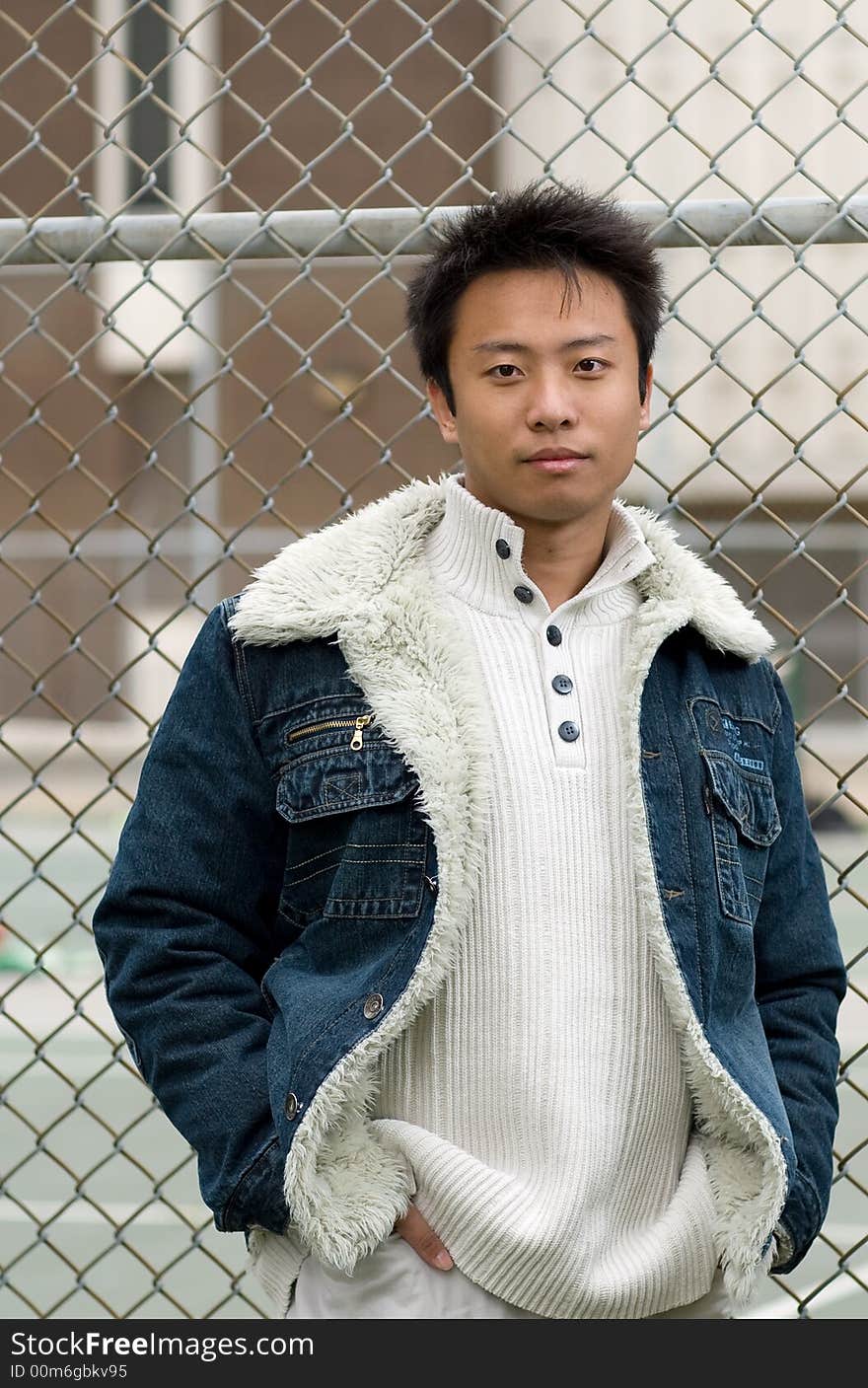 A boy stand outside tennis court wearing sports clothing. A boy stand outside tennis court wearing sports clothing