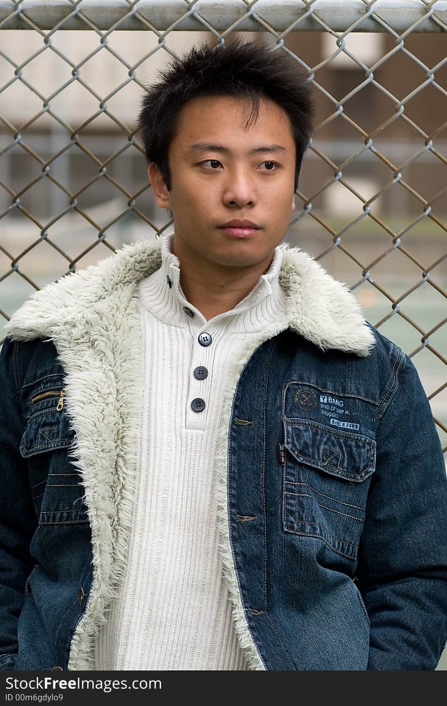 A boy stand outside tennis court wearing sports clothing. A boy stand outside tennis court wearing sports clothing