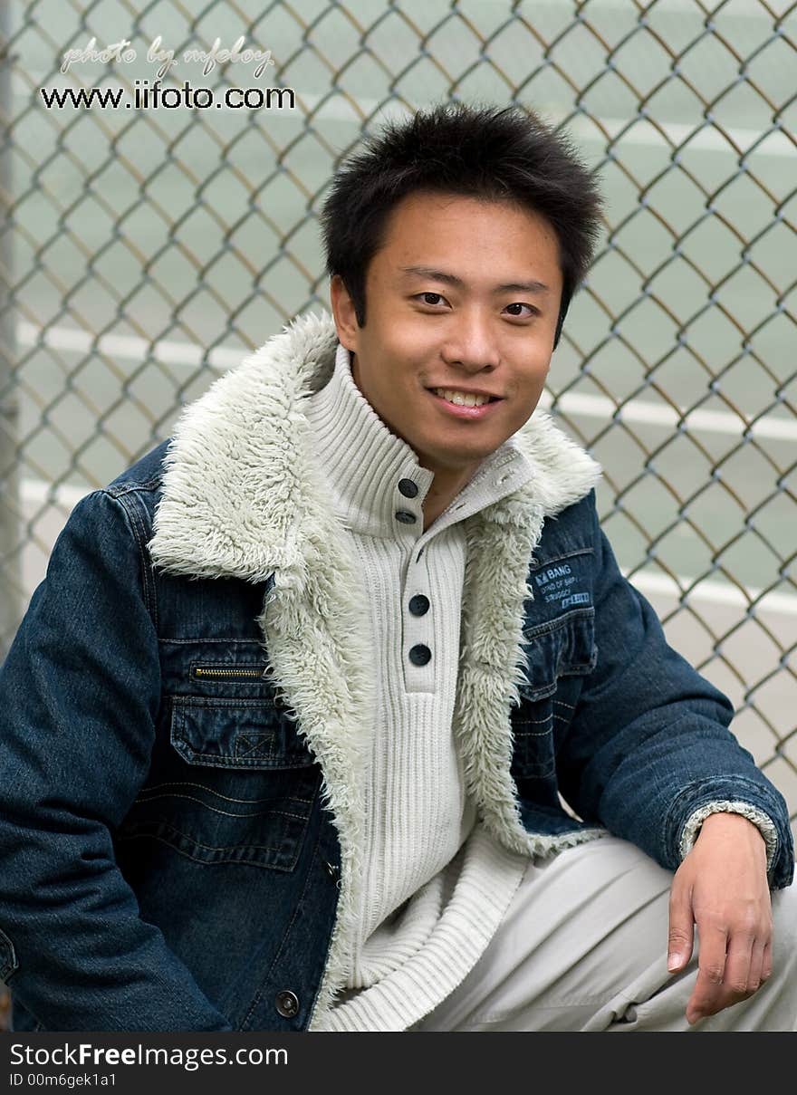 A boy standing outside tennis court wearing sports clothing. A boy standing outside tennis court wearing sports clothing