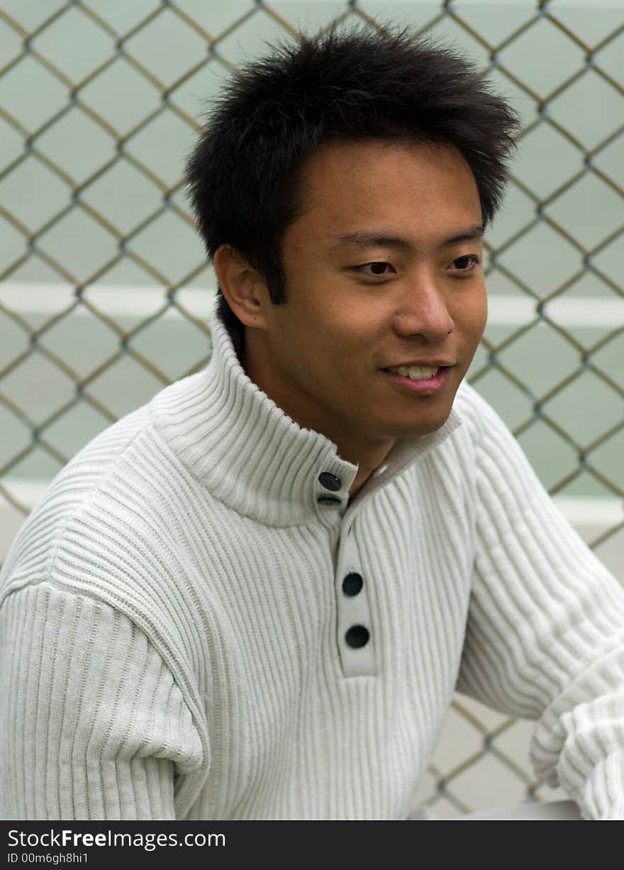 A boy squating outside tennis court wearing sports clothing. A boy squating outside tennis court wearing sports clothing