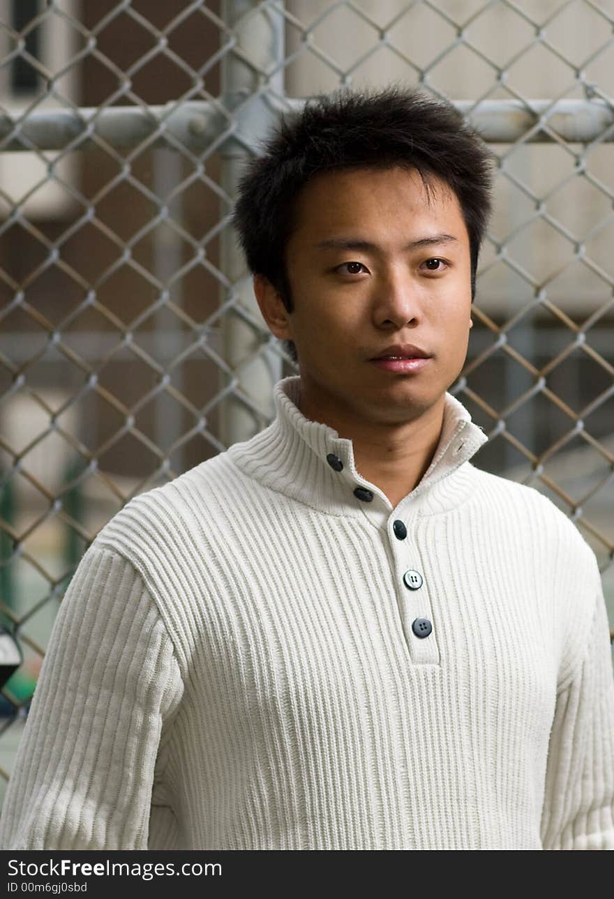 A boy standing outside tennis court wearing sports clothing. A boy standing outside tennis court wearing sports clothing