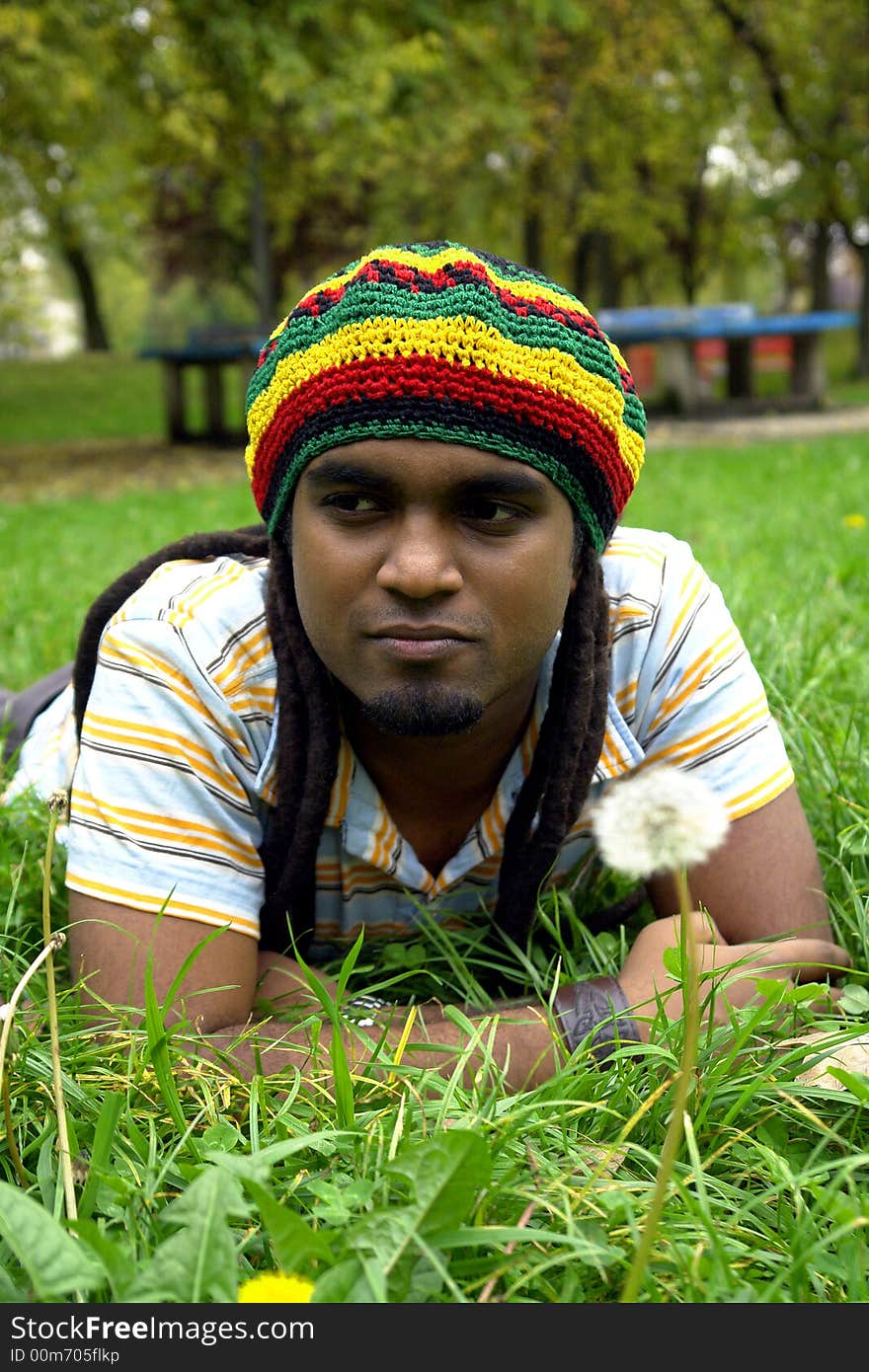 Sad Rastafarian Jamaican thinking laid on grass. Sad Rastafarian Jamaican thinking laid on grass