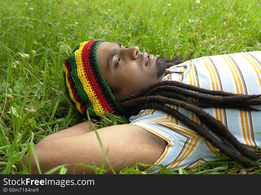 Sad Rastafarian Jamaican thinking laid on grass. Sad Rastafarian Jamaican thinking laid on grass